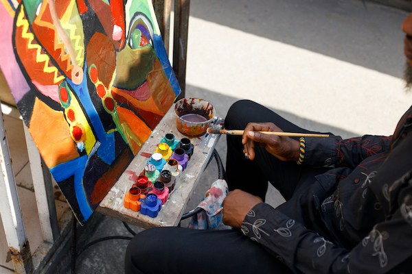 Artist painting a colorful canvas on the street during ArtPrize